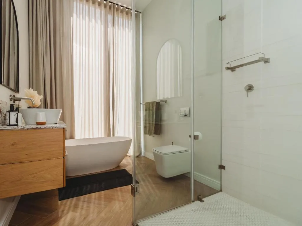 Modern bathroom with freestanding white tub, walk-in shower, and wooden vanity