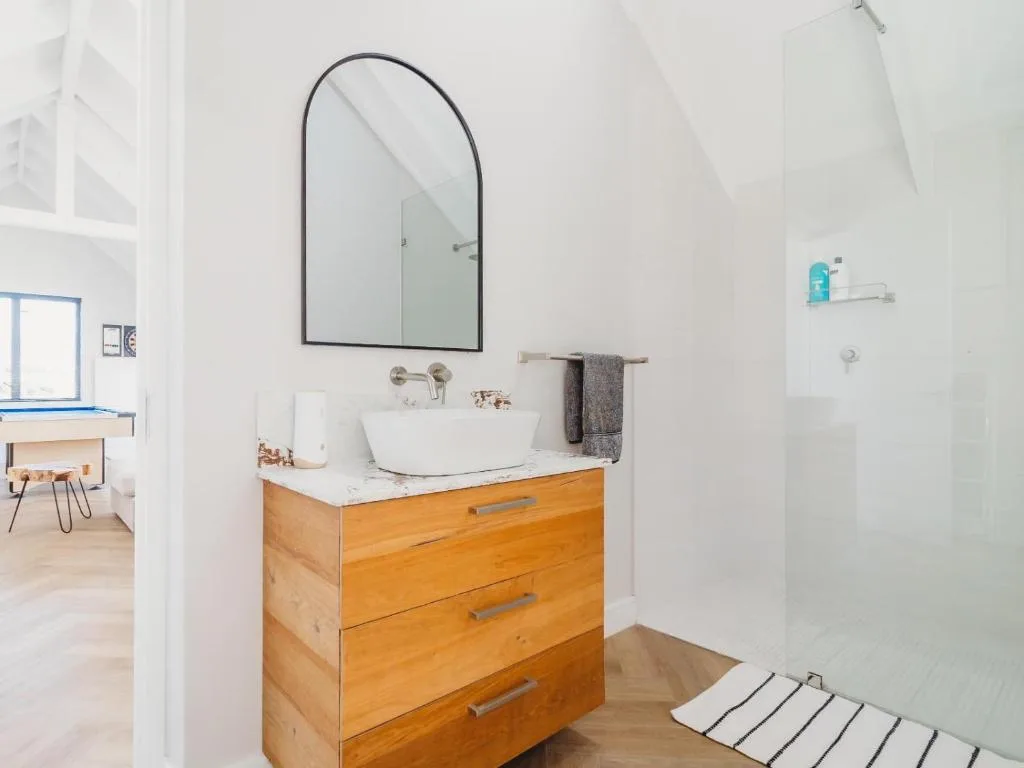 Modern bathroom with wooden vanity, round mirror, white vessel sink