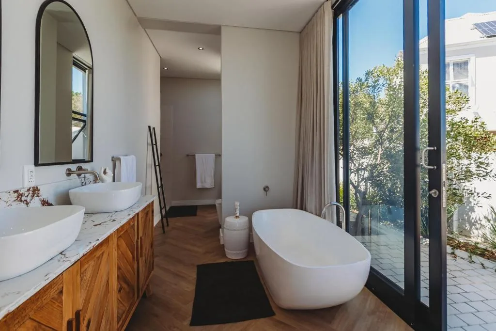 Modern bathroom with freestanding tub, dual vanity, and garden views