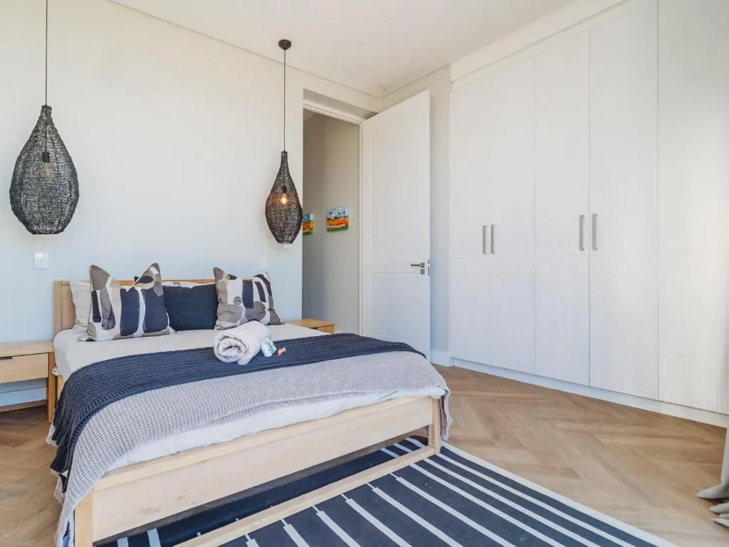 Spacious bedroom with queen bed, navy bedding, pendant lights, and built-in wardrobes