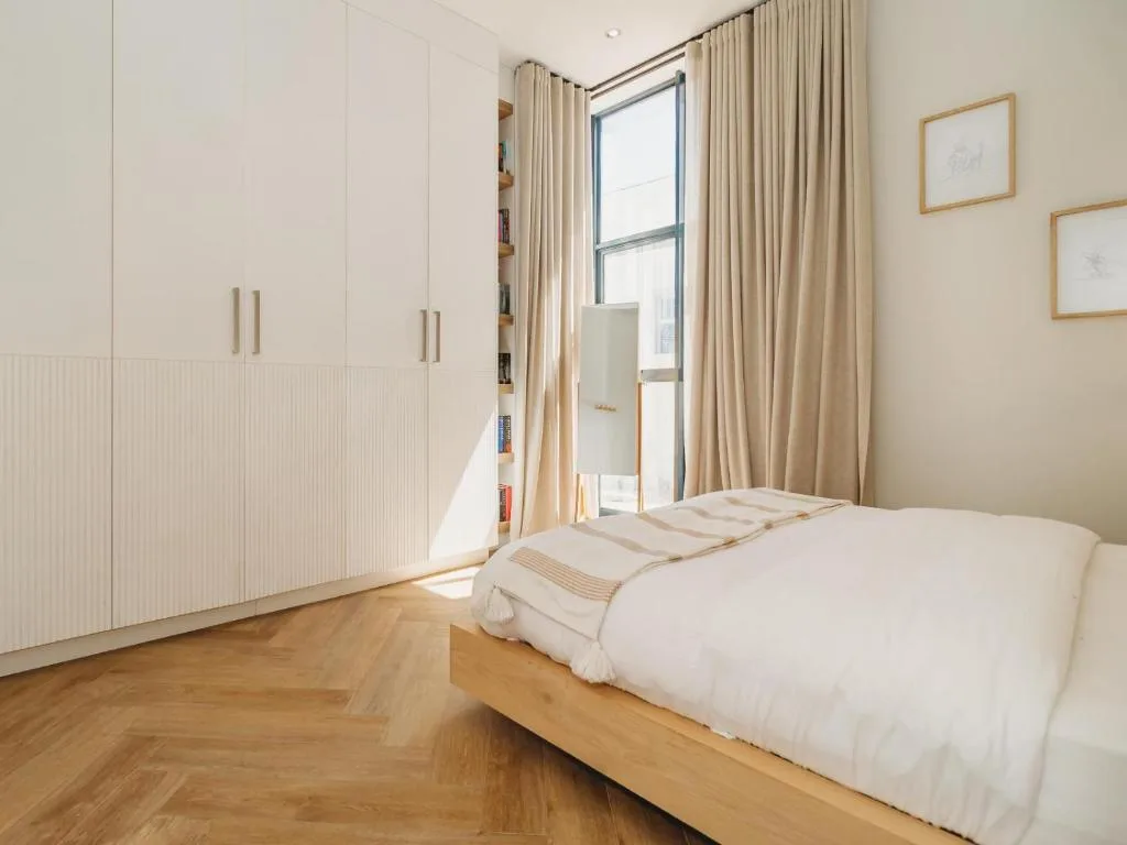 Bright bedroom with wooden bed, built-in wardrobes, and glass door access