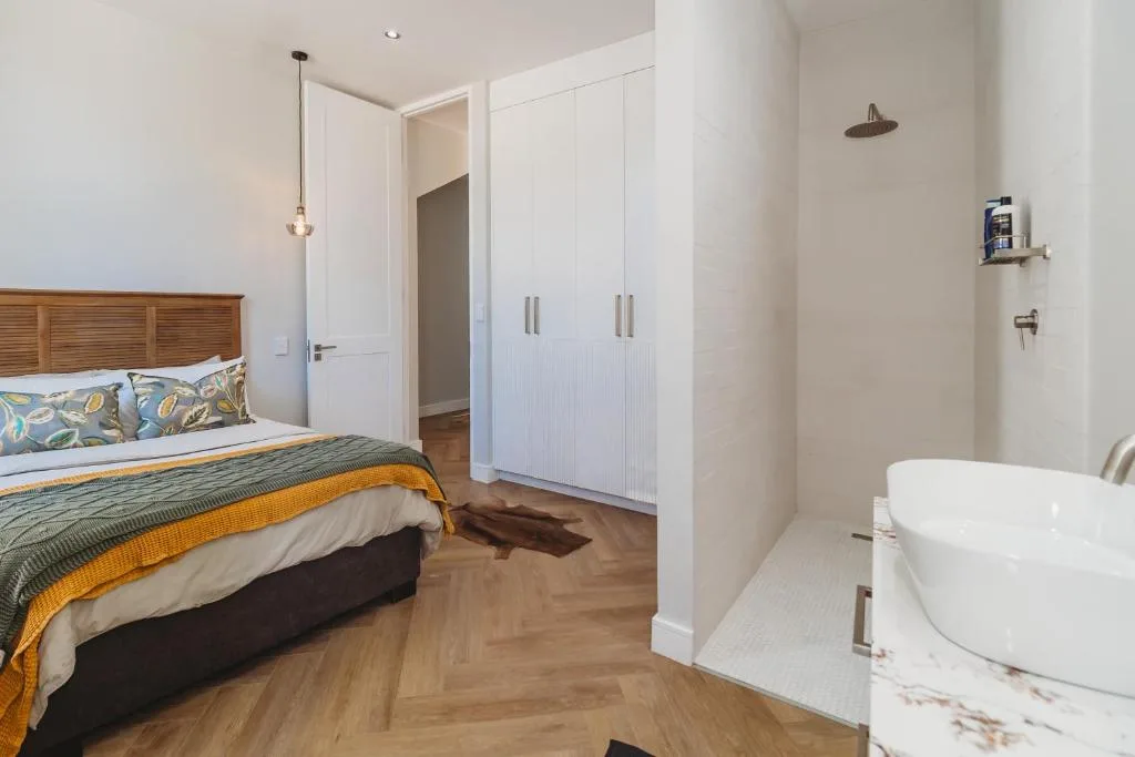 Bedroom with wooden bed frame and ensuite bathroom visible