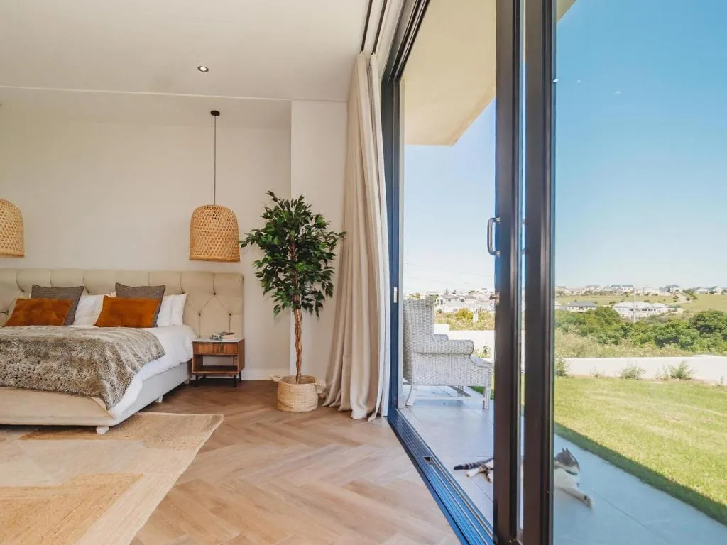 Modern bedroom with bed, pendant lights, and expansive garden views through sliding doors