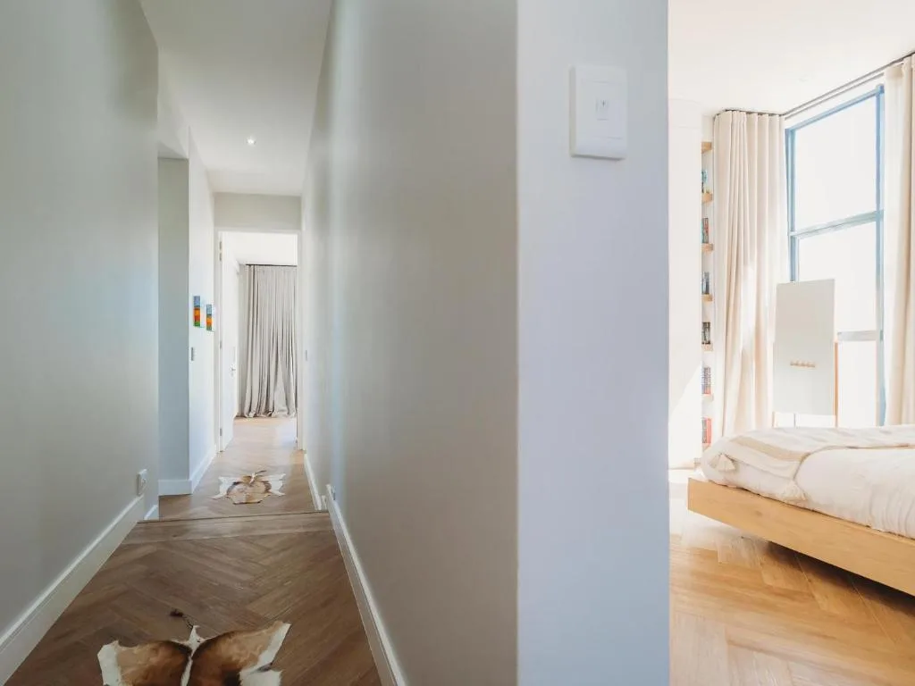 Bright bedroom with wooden bed frame and large window overlooking grounds