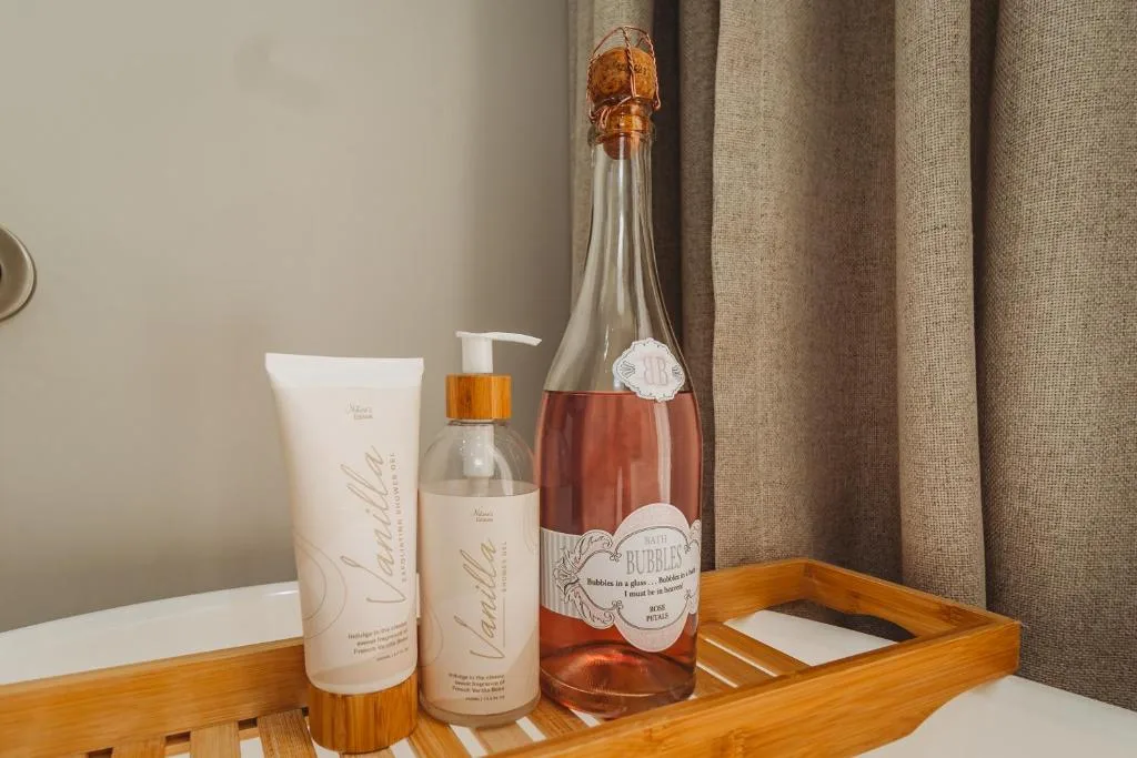 Luxury toiletries and rosé wine bottle displayed on wooden tray
