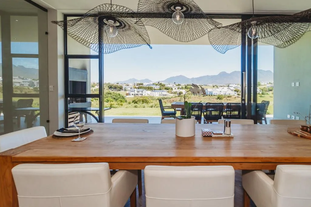 Wooden dining table with mountain views through expansive glass doors and decorative umbrellas