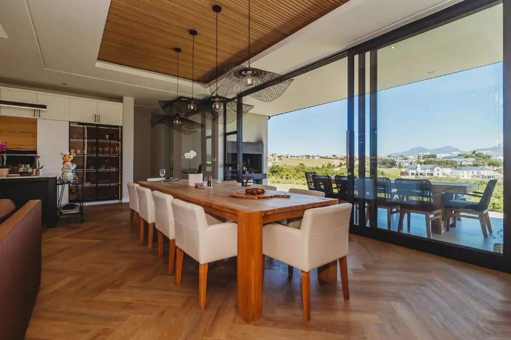 Modern dining area with wooden table, cream chairs, and mountain views