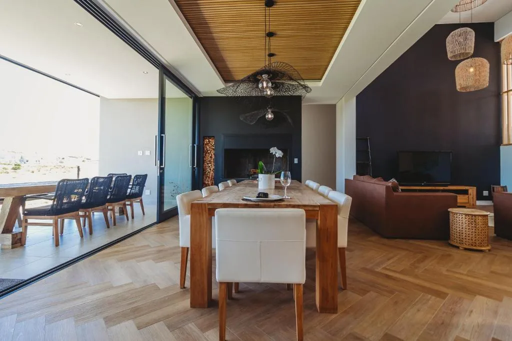 Open-plan dining area with wooden table and ocean view through glass doors