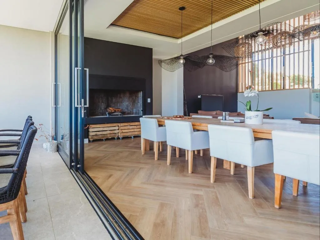 Modern dining area with wooden table, white chairs, and fireplace backdrop