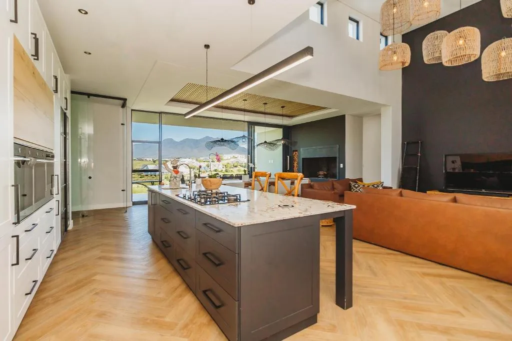 Modern kitchen with island, stove, and mountain views through large windows