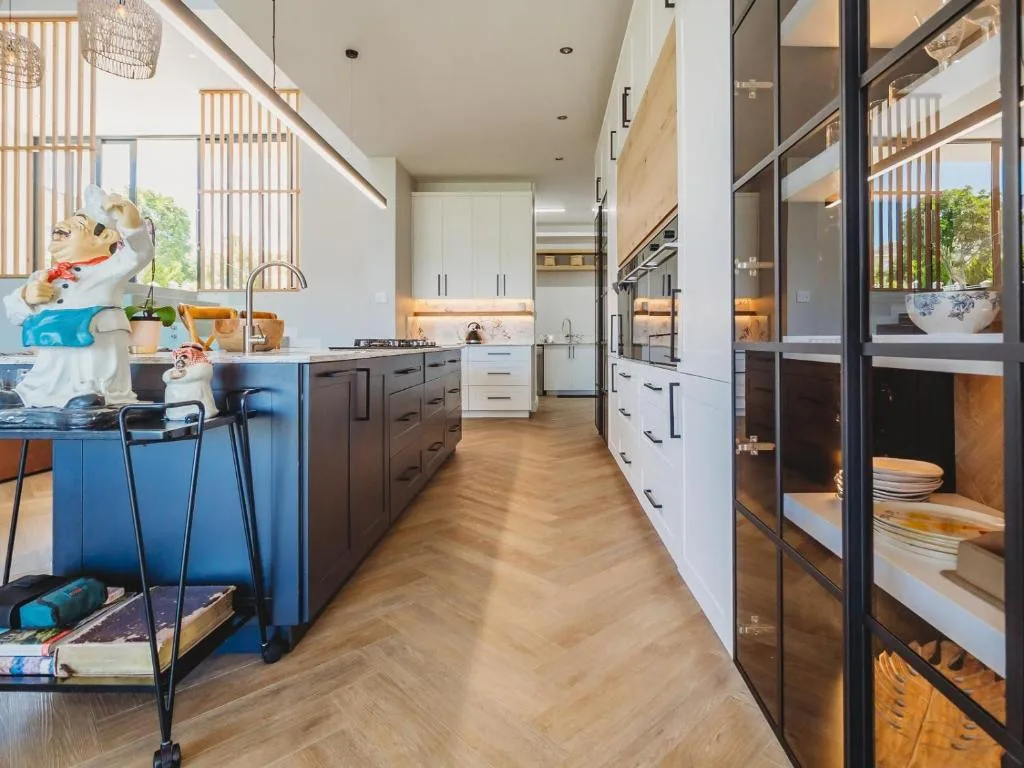 Modern kitchen with blue island, stainless steel appliances, and wooden flooring
