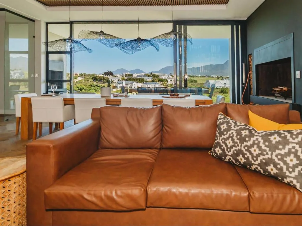 Modern lounge with brown leather sofa overlooking mountain views and garden estate