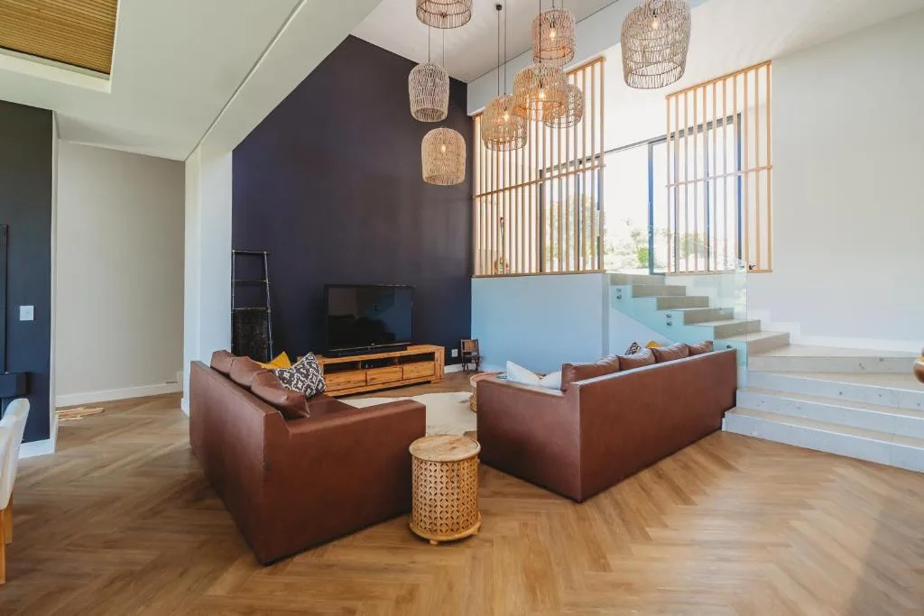 Modern living room with brown leather sofas, dark feature wall, and pendant lighting