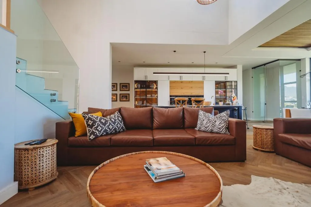 Modern open-plan lounge with brown leather sofa and round wooden coffee table