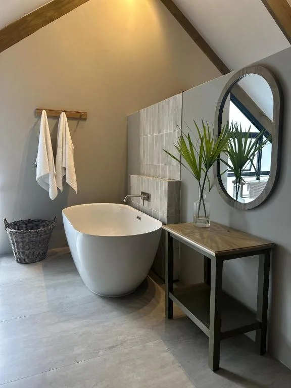 Modern bathroom with freestanding white bathtub and circular mirror