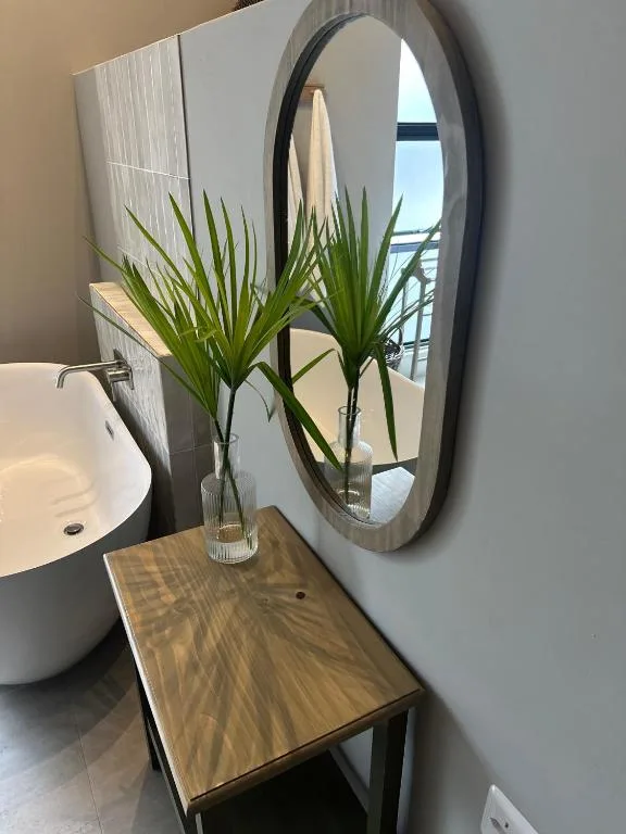 Modern bathroom vanity with round mirror and decorative green plant arrangement