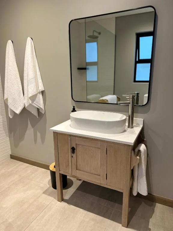 Modern bathroom vanity with round vessel sink and framed mirror