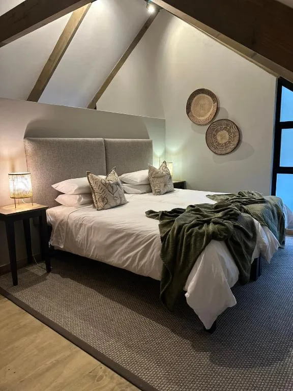 Spacious bedroom with upholstered headboard, white bedding, and vaulted ceiling