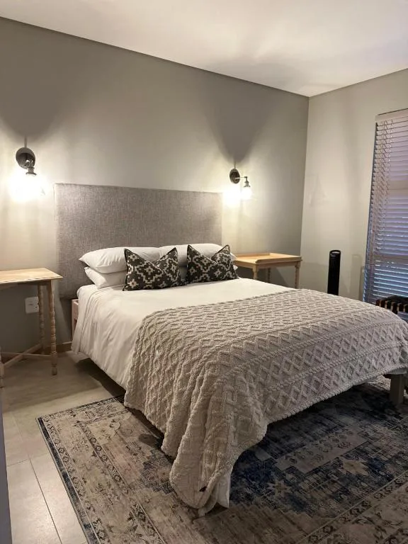 Modern bedroom with queen bed, gray upholstered headboard, bedside lamps