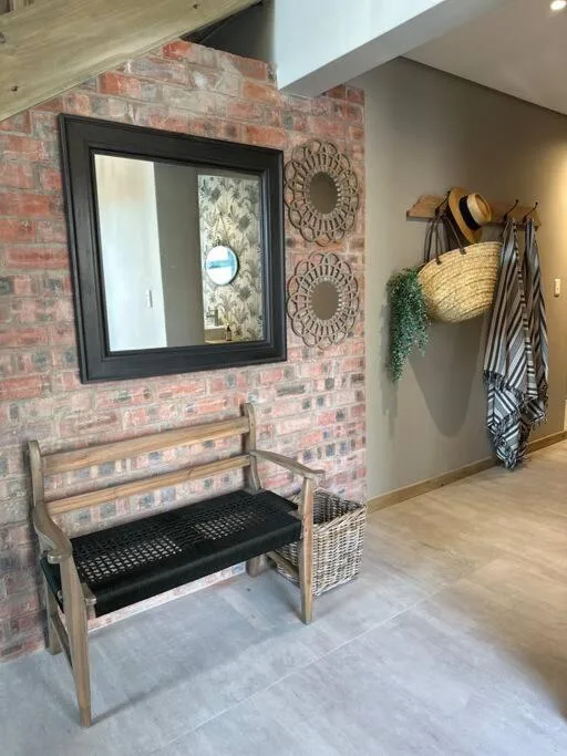 Entryway with rustic brick wall, wooden bench, and decorative hat rack