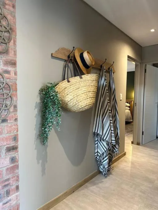 Entryway wall hooks display straw hat, striped towels, and decorative plants