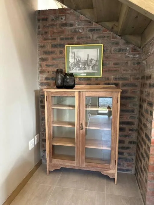 Wooden cabinet with glass doors against exposed brick wall