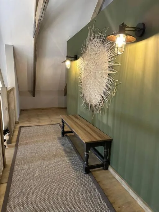 Modern hallway with green accent wall, decorative woven art installation, and wooden bench