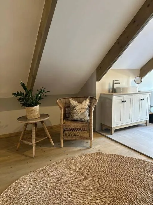Cozy attic nook with wicker chair, potted plant, and white vanity