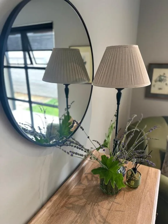 Decorative table lamps and fresh flowers with circular mirror reflection