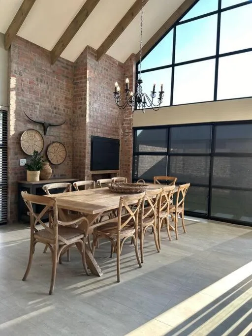 Modern dining area with wooden table and chairs, exposed brick walls