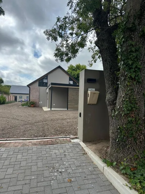 Modern villa entrance with paved driveway and large established tree