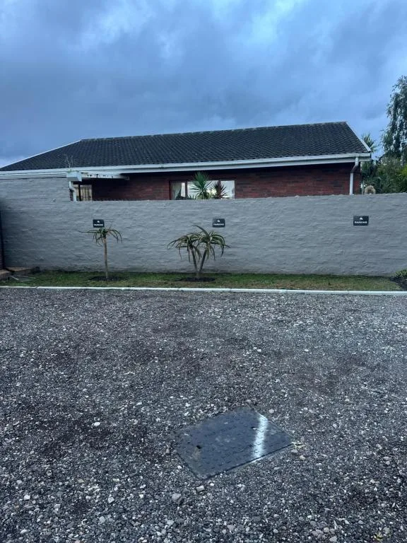 Modern single-story villa with brick and rendered walls, dark roof tiles, driveway approach