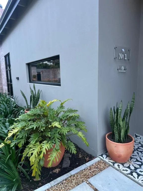 Modern white villa entrance with potted plants and unit number signage