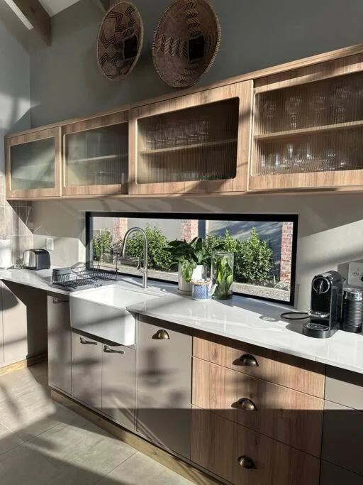 Modern kitchen with white countertops, wooden cabinetry, and window garden view