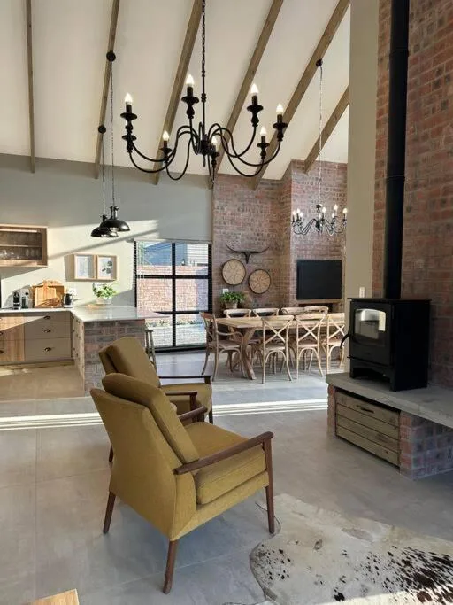 Open-plan lounge with mustard armchair, skylights, and exposed brick walls