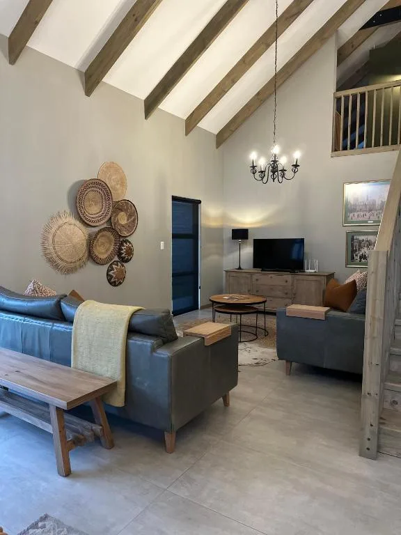 Open-plan lounge with blue sofa, TV unit, decorative wall baskets, and pendant lighting