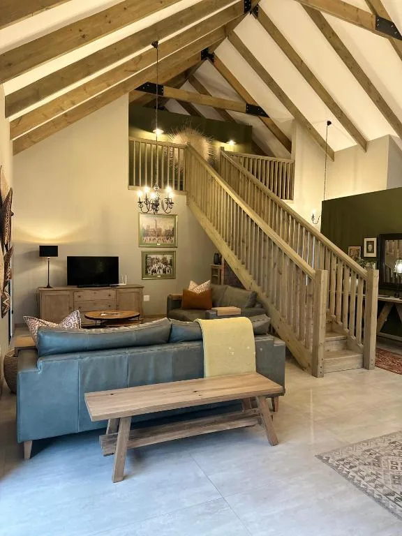 Open-plan lounge with blue sofa, wooden table, and wooden staircase