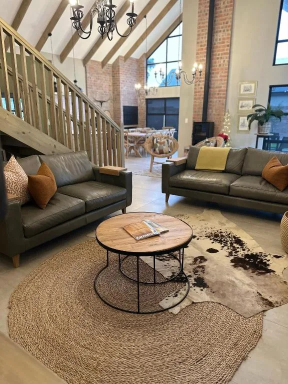 Modern lounge with leather sofas, round wooden table, and exposed brick architecture