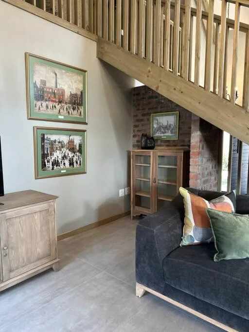 Modern lounge with dark sofa, framed artwork, wooden furniture, and brick fireplace