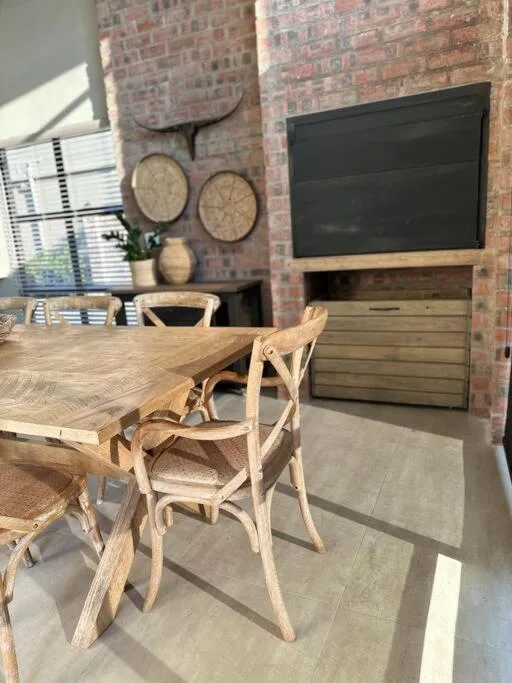Modern lounge with wooden dining table, chairs, and mounted television on brick wall