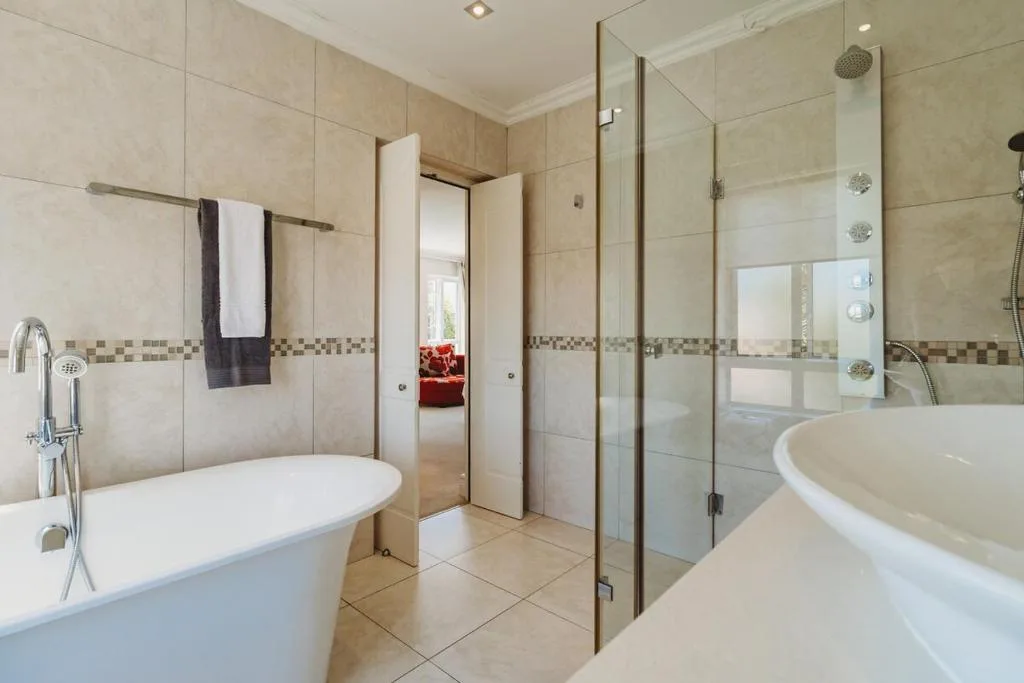Spacious bathroom with freestanding bathtubs, walk-in shower, and neutral tile finishes