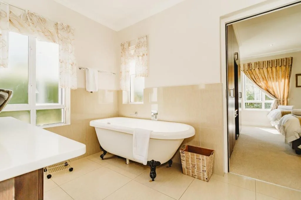 Spacious bathroom with freestanding clawfoot bathtub and cream walls
