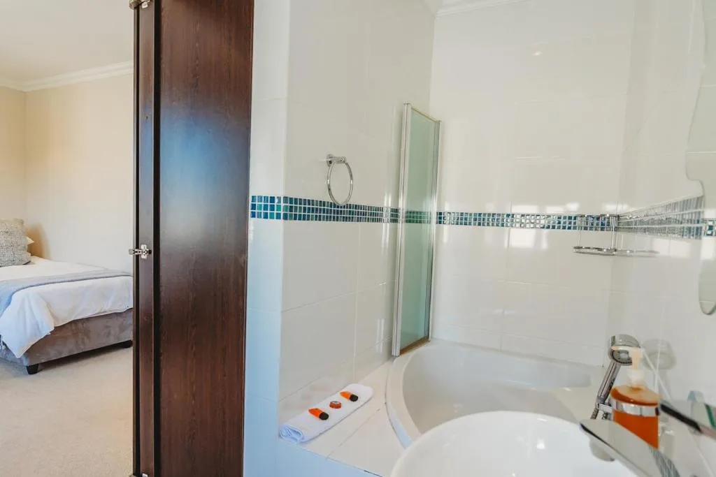 Modern bathroom with white tiles, glass shower enclosure, and blue mosaic trim