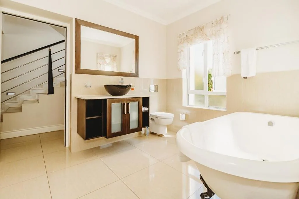 Spacious bathroom with freestanding bathtub, dark vanity sink, and window