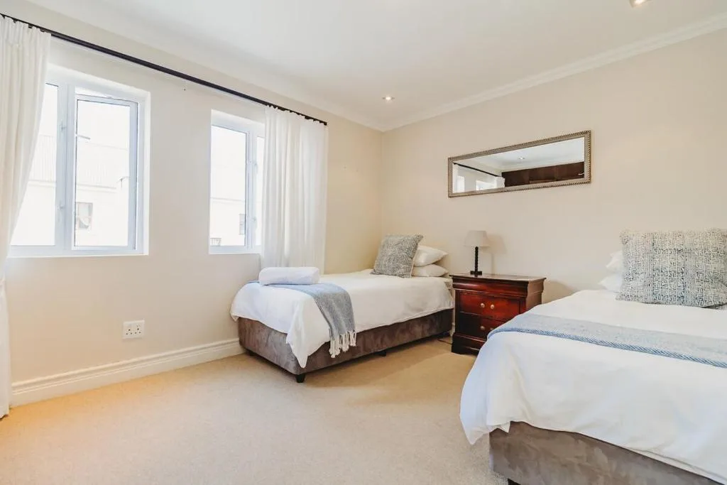 Spacious bedroom with two single beds and wooden bedside table