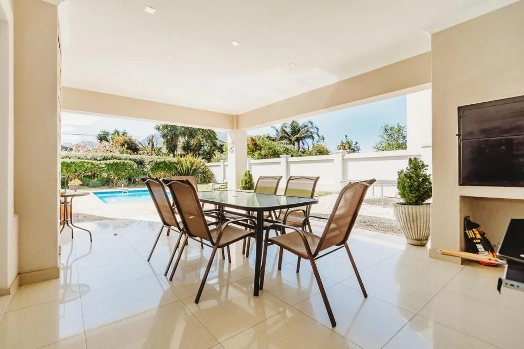 Covered patio with dining table, chairs, and pool view beyond