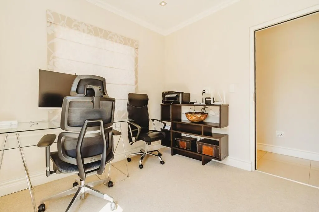 Modern home office workspace with ergonomic chairs and desk storage shelving