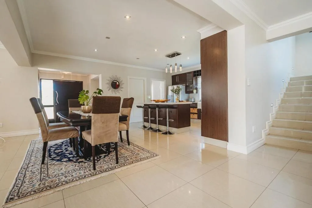 Open-plan dining area with dark wood table and cream upholstered chairs