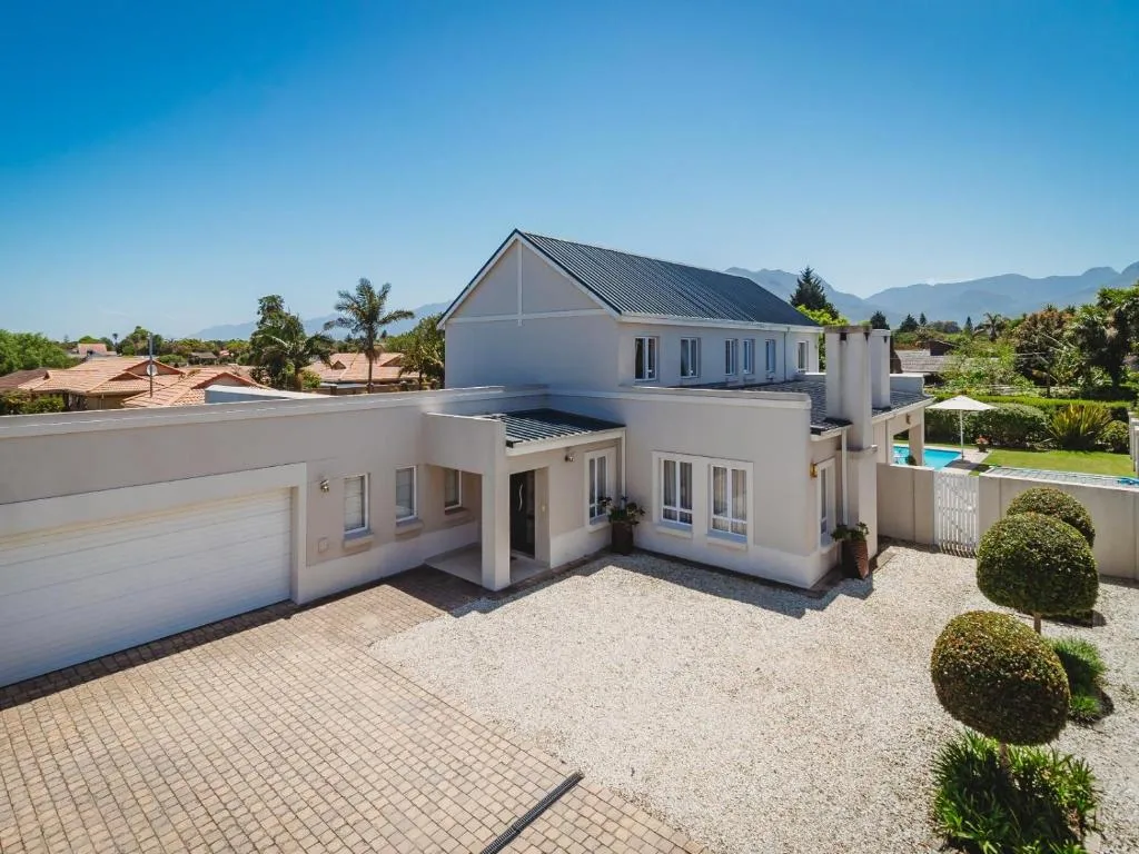 Modern white home with garage, driveway, and mountain views beyond