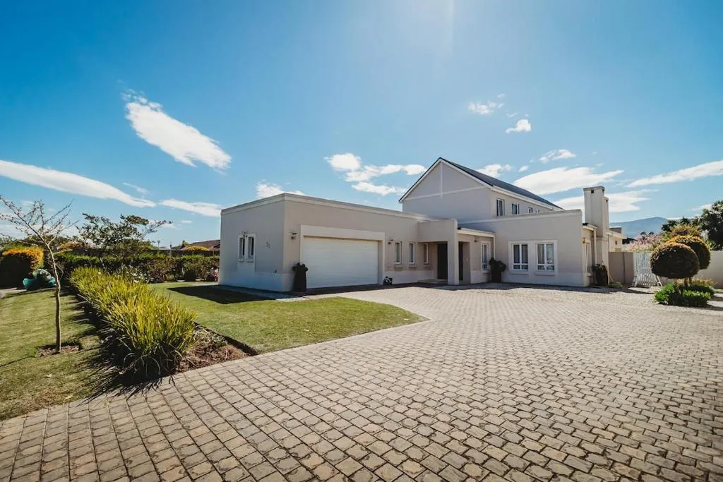 Modern white house with garage and manicured lawn under blue sky